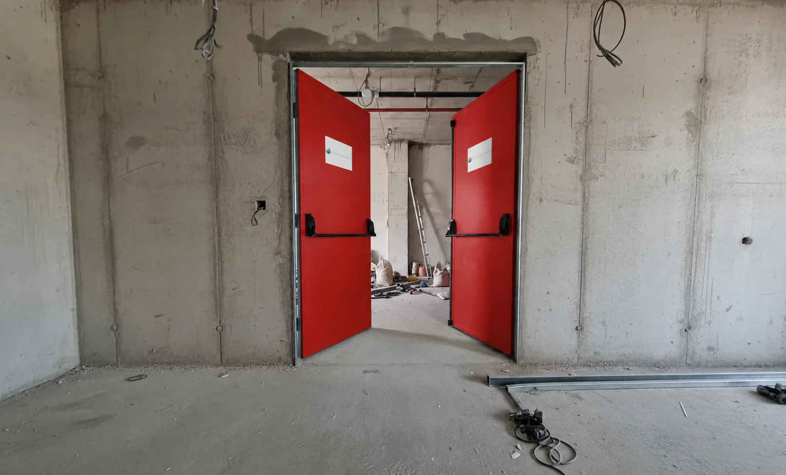 Porta de duas folhas abertas com acabamento vermelho e barras antipânico.